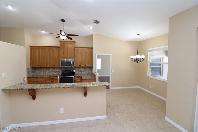 kitchen with range, tasteful backsplash, light tile patterned floors, hanging light fixtures, and a kitchen breakfast bar