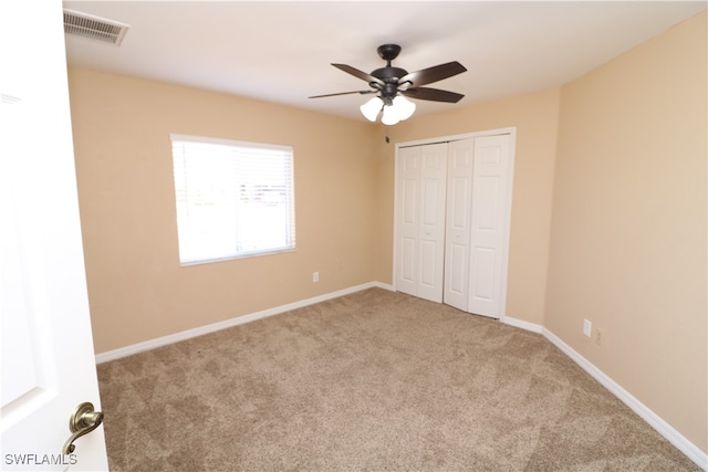 unfurnished bedroom with light carpet, a closet, and ceiling fan