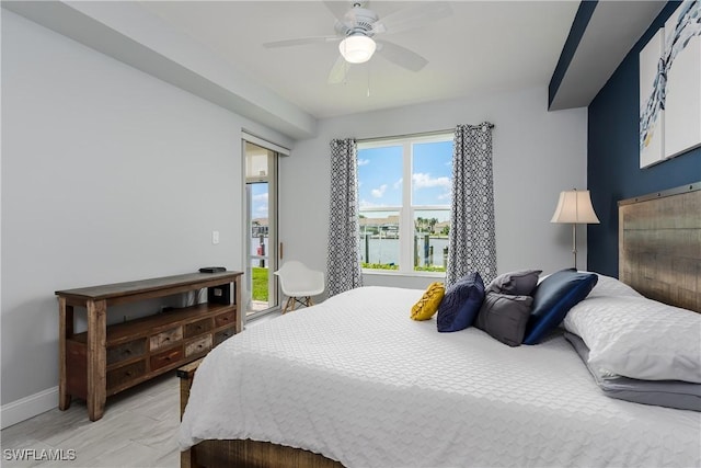 bedroom with a water view, ceiling fan, and baseboards