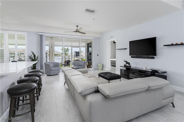 living room featuring baseboards, a wealth of natural light, visible vents, and a ceiling fan