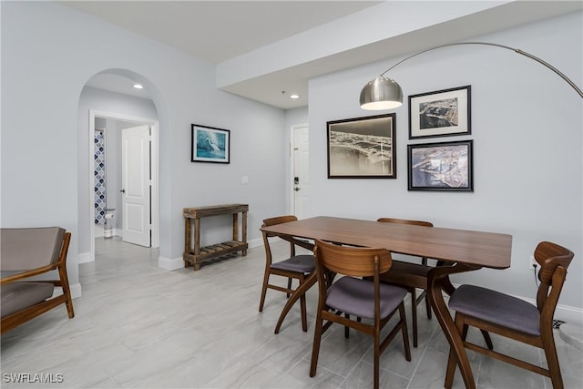 dining area featuring baseboards, arched walkways, and recessed lighting