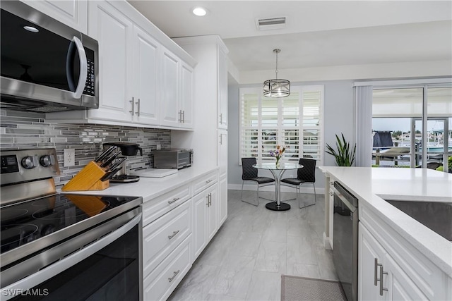 kitchen featuring stainless steel appliances, hanging light fixtures, light countertops, and white cabinets