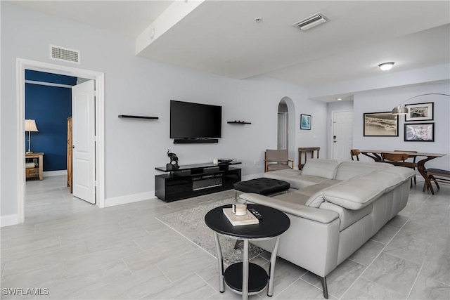 living room featuring arched walkways, visible vents, and baseboards