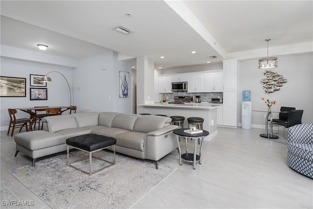 living area featuring recessed lighting, visible vents, and baseboards