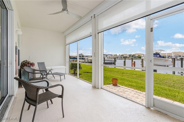 sunroom with ceiling fan and a water view