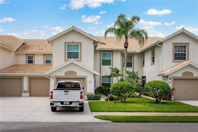 multi unit property featuring driveway, a tile roof, a front lawn, and stucco siding