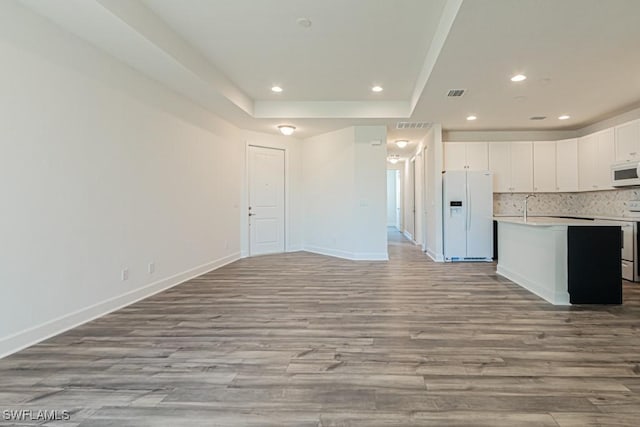 kitchen featuring white cabinetry, a kitchen island with sink, white appliances, and light wood-type flooring