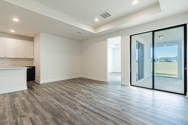 unfurnished living room with a raised ceiling and light wood-type flooring