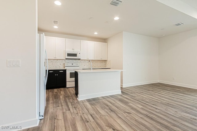 kitchen featuring decorative backsplash, white appliances, a kitchen island with sink, light hardwood / wood-style flooring, and white cabinetry