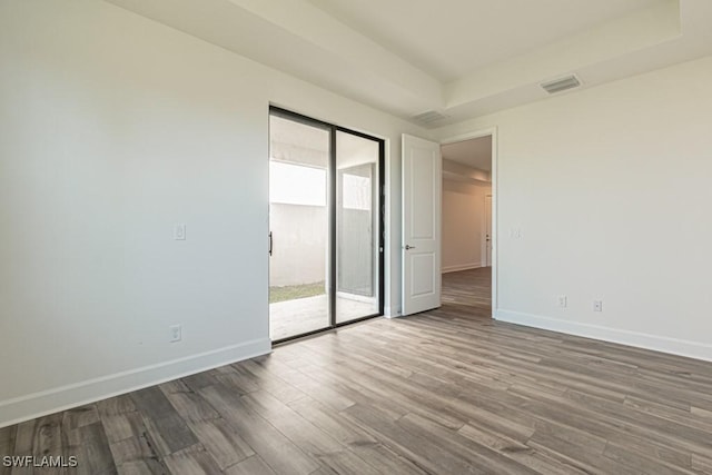 empty room with plenty of natural light, dark hardwood / wood-style floors, and a raised ceiling