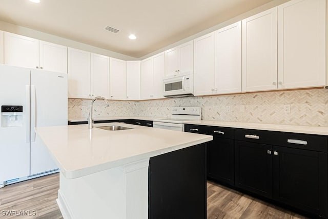 kitchen featuring light wood-type flooring, white appliances, a kitchen island with sink, and sink