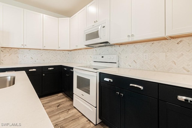 kitchen with tasteful backsplash, white cabinetry, light hardwood / wood-style flooring, and white appliances