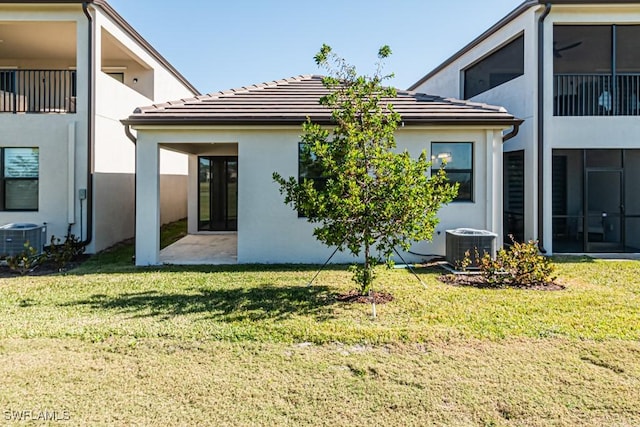 rear view of property featuring central air condition unit and a yard