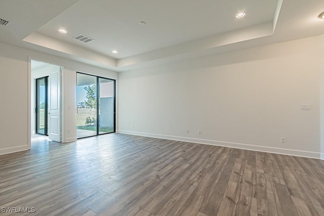 spare room featuring hardwood / wood-style flooring and a tray ceiling