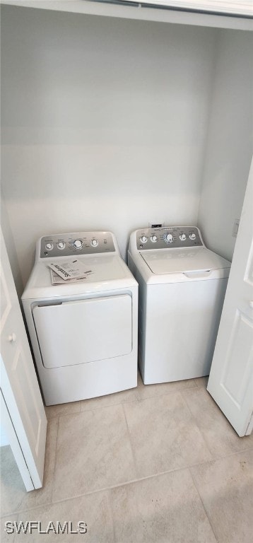 laundry area with light tile patterned floors and washing machine and clothes dryer