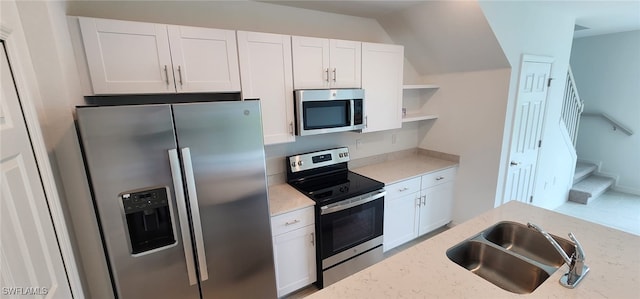 kitchen with appliances with stainless steel finishes, white cabinets, sink, and light stone countertops