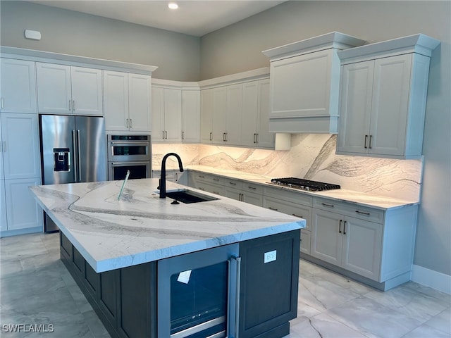 kitchen with light stone counters, an island with sink, appliances with stainless steel finishes, and sink