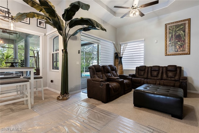 living room with a raised ceiling and ceiling fan