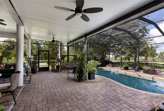 view of pool with a patio area, ceiling fan, and glass enclosure