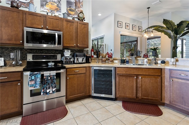 kitchen with appliances with stainless steel finishes, beverage cooler, hanging light fixtures, and backsplash