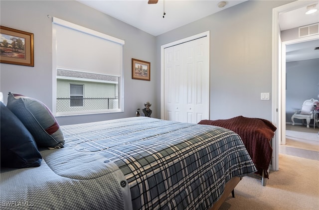 carpeted bedroom with ceiling fan and a closet