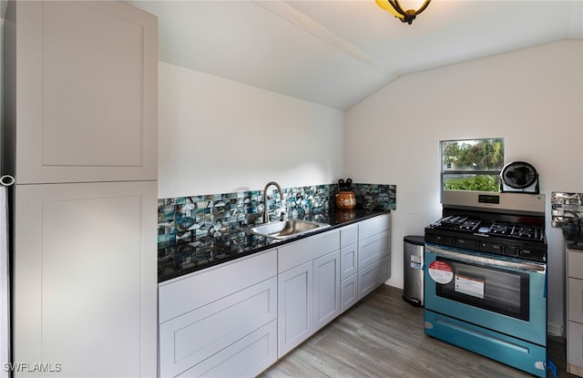 kitchen with lofted ceiling, sink, light hardwood / wood-style floors, gas stove, and white cabinets