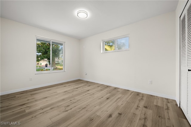 unfurnished bedroom featuring multiple windows, a closet, and light wood-type flooring