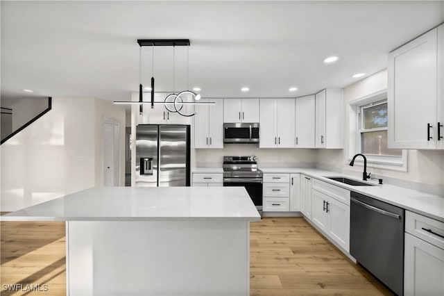 kitchen featuring appliances with stainless steel finishes, white cabinetry, a kitchen island, pendant lighting, and sink