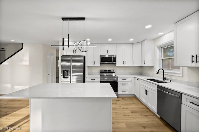 kitchen with sink, white cabinetry, hanging light fixtures, stainless steel appliances, and a kitchen island