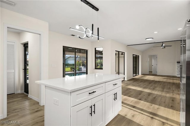 kitchen with light hardwood / wood-style flooring, ceiling fan, white cabinetry, hanging light fixtures, and a center island