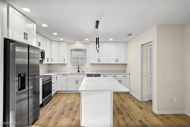 kitchen with pendant lighting, light wood-type flooring, sink, white cabinetry, and stainless steel appliances