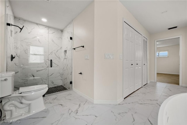bathroom with toilet, a shower with shower door, and a wealth of natural light