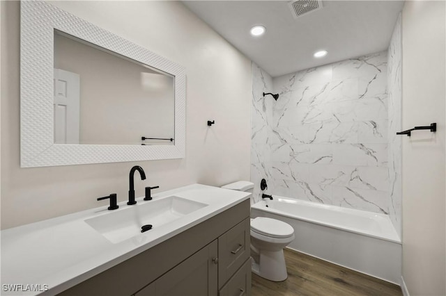full bathroom with tiled shower / bath, hardwood / wood-style floors, vanity, and toilet