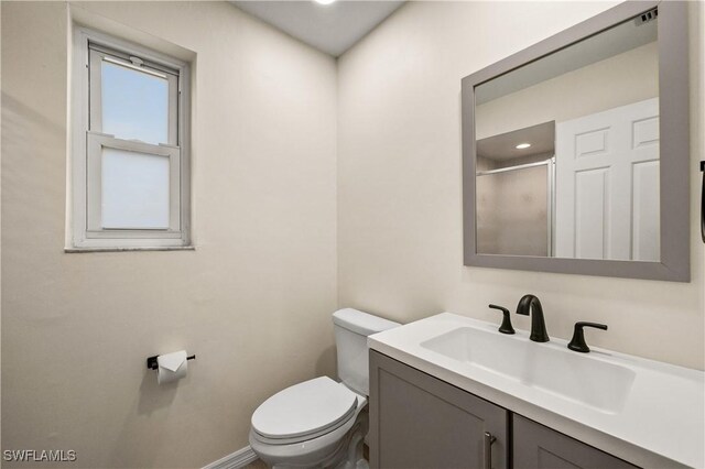 bathroom featuring vanity, walk in shower, and toilet