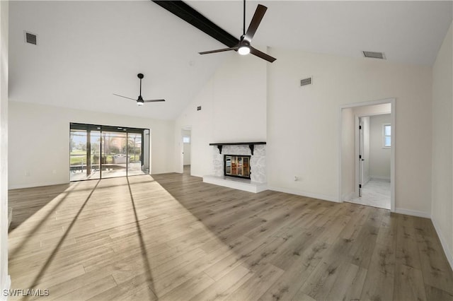 unfurnished living room featuring beam ceiling, a fireplace, ceiling fan, and light wood-type flooring