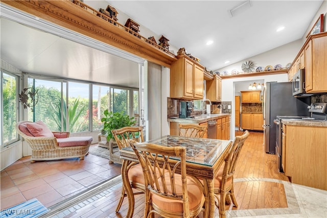 dining room featuring sink, vaulted ceiling, and light wood-type flooring