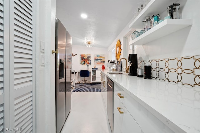 kitchen featuring dishwasher, light stone counters, white cabinetry, and sink