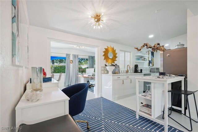 kitchen with white cabinets, a kitchen island, a notable chandelier, and sink