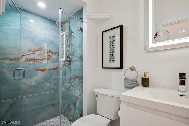 bathroom featuring a shower with door, vanity, and toilet