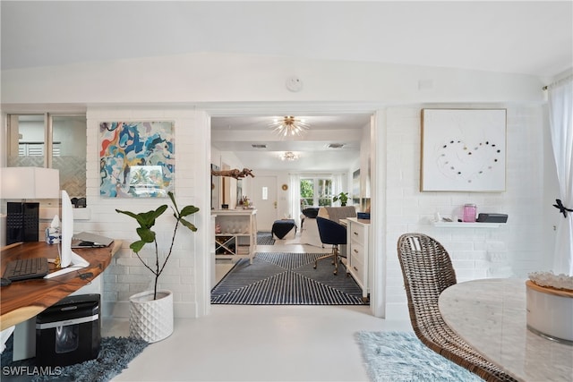 entryway with a notable chandelier, concrete floors, and vaulted ceiling