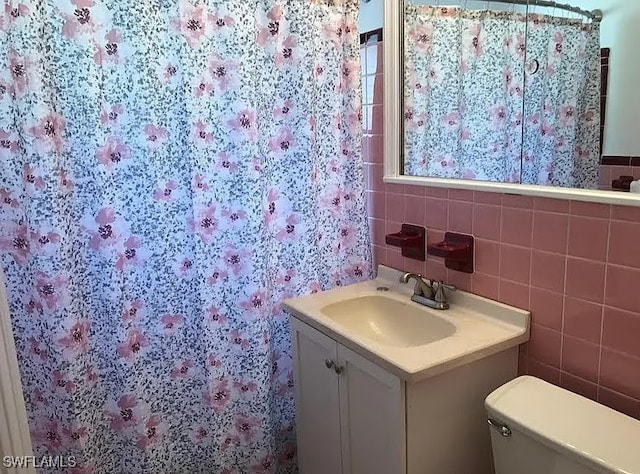 bathroom with vanity, tile walls, toilet, and decorative backsplash