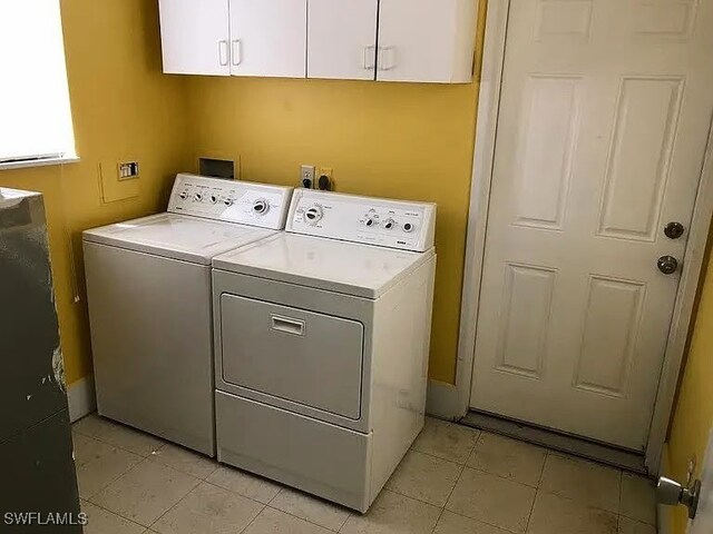 laundry room with light tile patterned flooring, cabinets, and washer and dryer