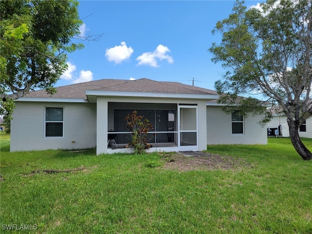 rear view of house featuring a sunroom and a yard