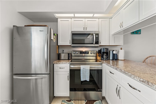 kitchen with appliances with stainless steel finishes, light tile patterned floors, and white cabinets