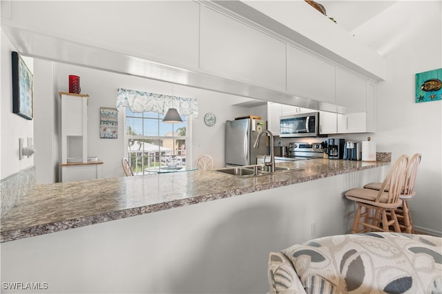 kitchen featuring appliances with stainless steel finishes, kitchen peninsula, lofted ceiling, and white cabinetry