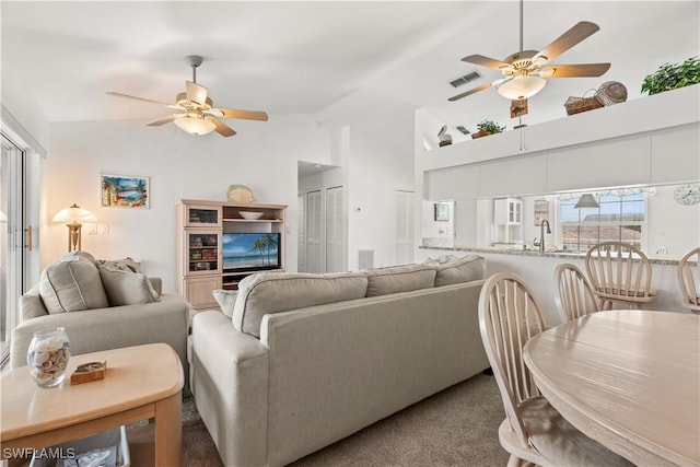 carpeted living room with high vaulted ceiling, sink, and ceiling fan