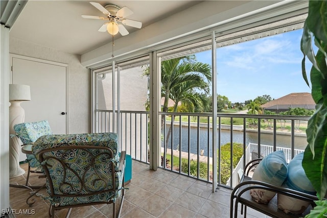 sunroom featuring ceiling fan and a water view