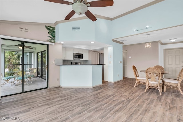 kitchen featuring white cabinets, crown molding, light hardwood / wood-style flooring, and ceiling fan with notable chandelier