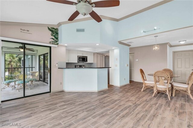 kitchen with white cabinetry, crown molding, hanging light fixtures, and light hardwood / wood-style floors