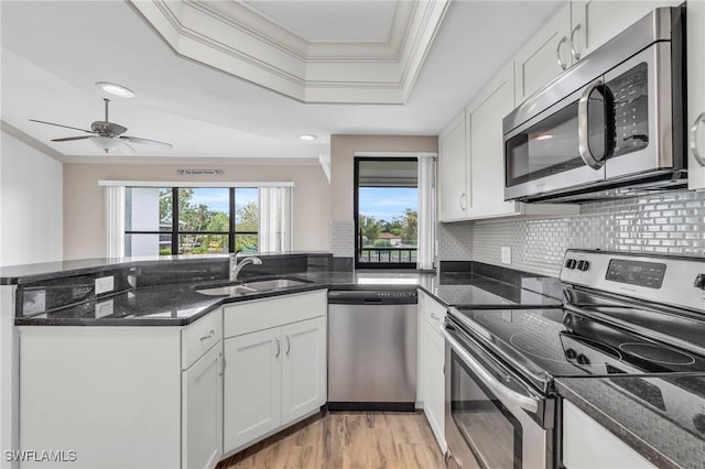 kitchen with appliances with stainless steel finishes, sink, dark stone counters, and white cabinets